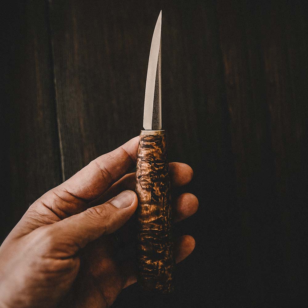 Rosellis finska handgjorda slöjdkniv med handtag av betsad masurbjörk. Blad av kolstål med en Scandi Grind Zero design. Levereras med ett handgjord läderfordral.