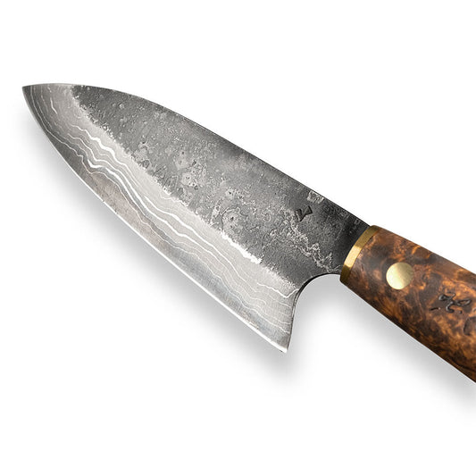 Handgjord kökskniv i damaskusstål, tillverkad i Rosellis fabrik i Finland. Damaskusstålet består av 37 lager stål. Kniven har ett skaft av betsad masurbjörk och levereras med ett handgjort läderfodral.