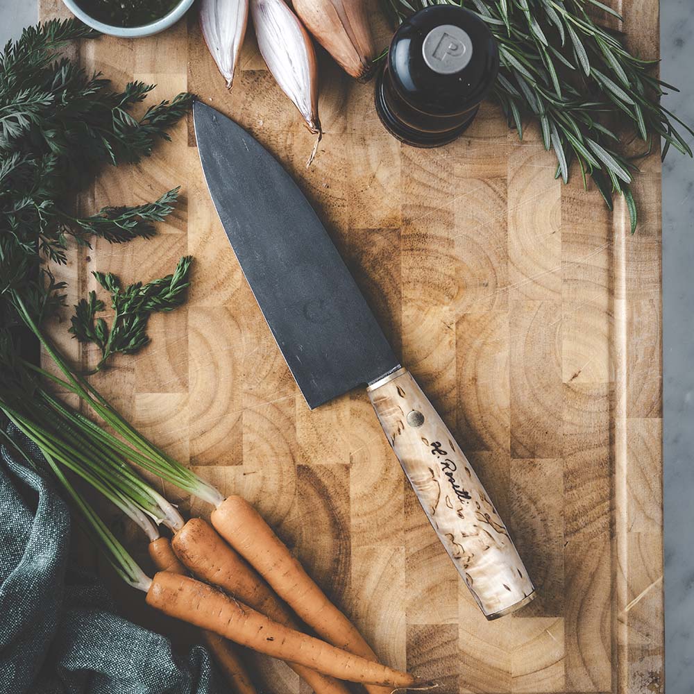 Roselli's finska handgjorda japanska kökskniv i modell "Santoku-kniv". Med blad av kolstål och handtag av masurbjörk. Levereras med ett handgjort fodral av finskt naturgarvat läder. 