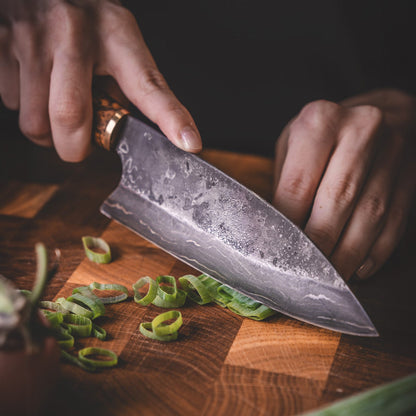 Handgjord kökskniv i damaskusstål, tillverkad i Rosellis fabrik i Finland. Damaskusstålet består av 37 lager stål. Kniven har ett skaft av betsad masurbjörk och levereras med ett handgjort läderfodral.