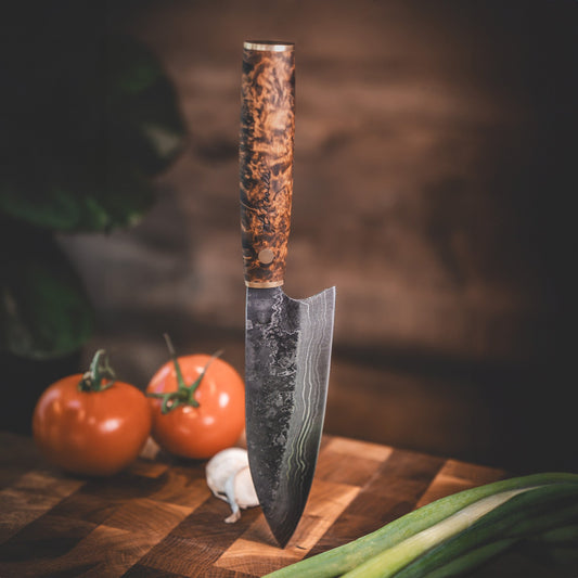 Handgjord kökskniv i damaskusstål, tillverkad i Rosellis fabrik i Finland. Damaskusstålet består av 37 lager stål. Kniven har ett skaft av betsad masurbjörk och levereras med ett handgjort läderfodral.